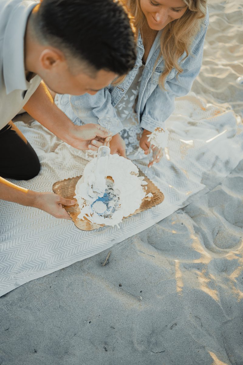 Couple cutting the gender reveal cake on the beach